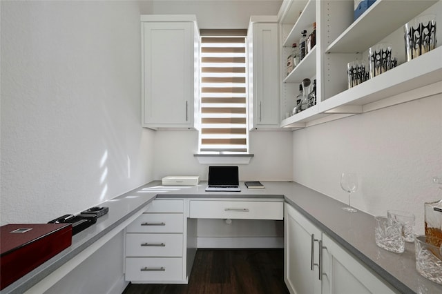 home office featuring dark wood-type flooring and built in desk