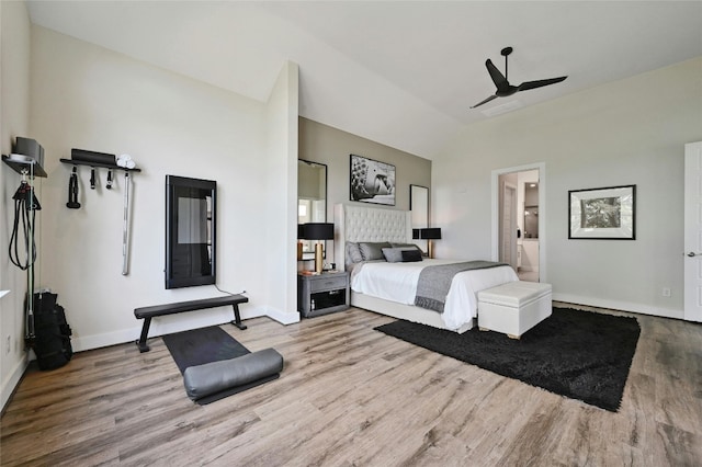 bedroom featuring ceiling fan, connected bathroom, light hardwood / wood-style flooring, and lofted ceiling