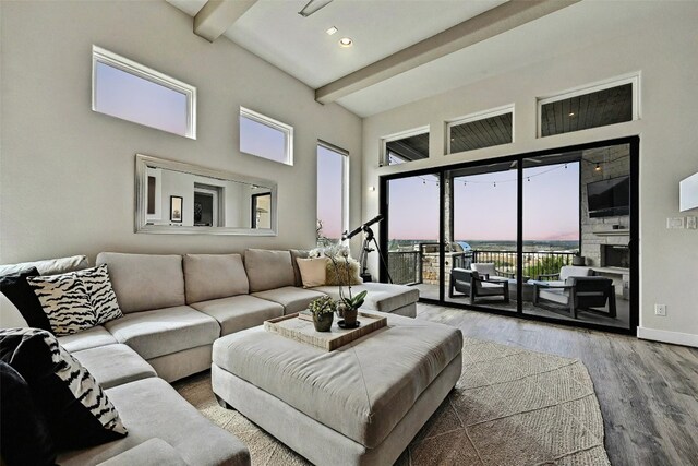 living room featuring a towering ceiling, hardwood / wood-style floors, and beamed ceiling