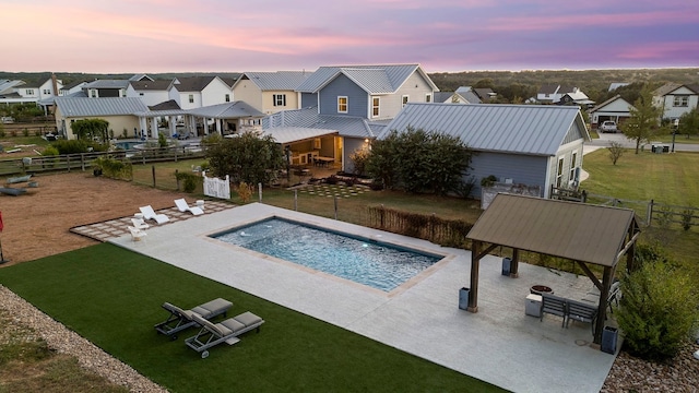 pool at dusk with a patio and a yard