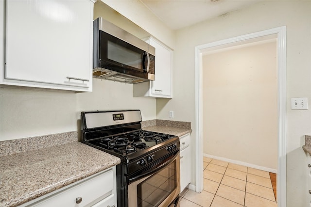 kitchen with light stone countertops, range with gas cooktop, white cabinetry, and light tile patterned floors