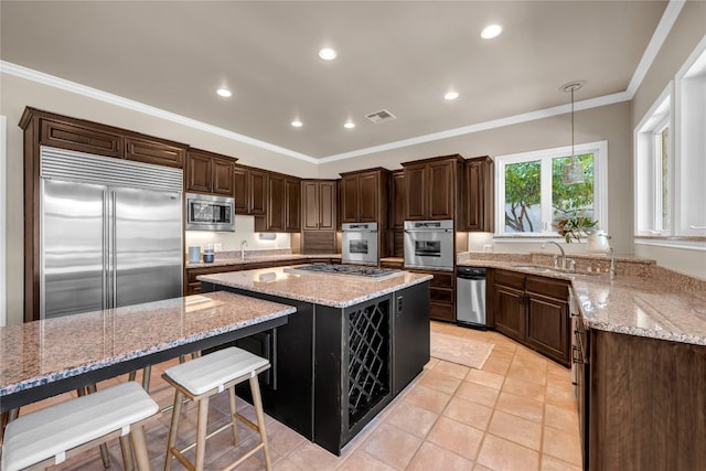 kitchen featuring light stone countertops, hanging light fixtures, a large island, and built in appliances