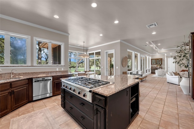 kitchen featuring stainless steel appliances, a healthy amount of sunlight, light stone counters, and a kitchen island