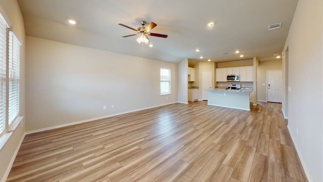 unfurnished living room featuring ceiling fan and light wood-type flooring