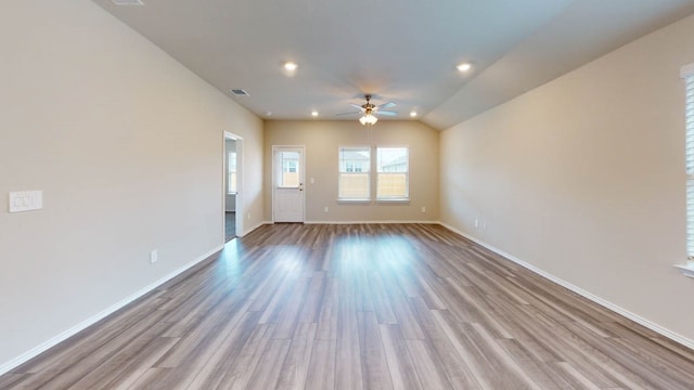 spare room with light wood-type flooring, vaulted ceiling, and ceiling fan