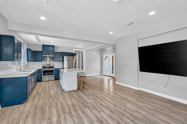 kitchen with blue cabinetry, sink, a center island, a kitchen breakfast bar, and stainless steel appliances