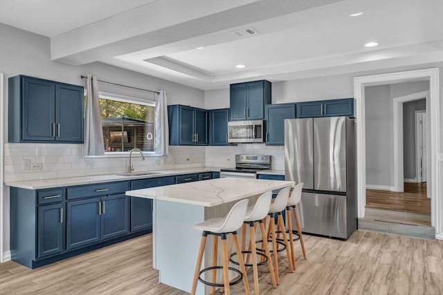 kitchen with blue cabinets, sink, a breakfast bar area, a kitchen island, and stainless steel appliances