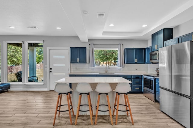 kitchen featuring sink, a breakfast bar area, stainless steel appliances, and blue cabinetry