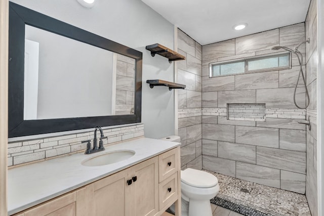 bathroom with vanity, toilet, decorative backsplash, and a tile shower