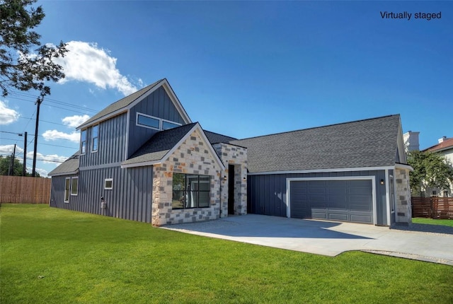 view of front of home with an attached garage, fence, concrete driveway, stone siding, and a front yard