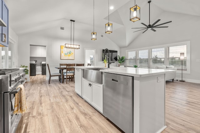 kitchen featuring pendant lighting, stainless steel appliances, an island with sink, and light hardwood / wood-style flooring