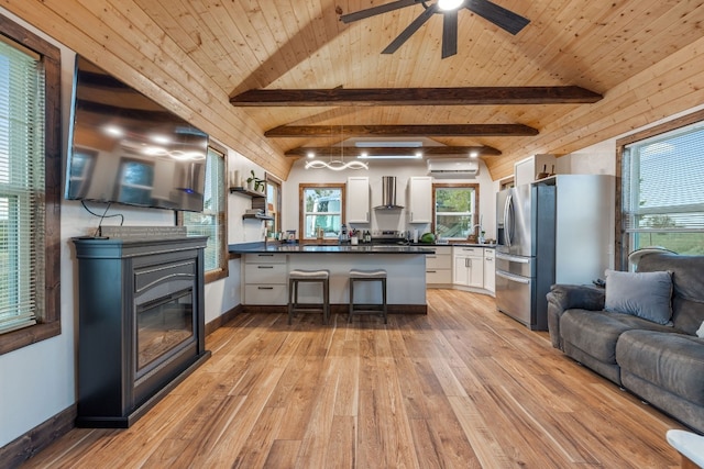 kitchen featuring white cabinets, stainless steel fridge with ice dispenser, light wood-type flooring, lofted ceiling with beams, and an AC wall unit