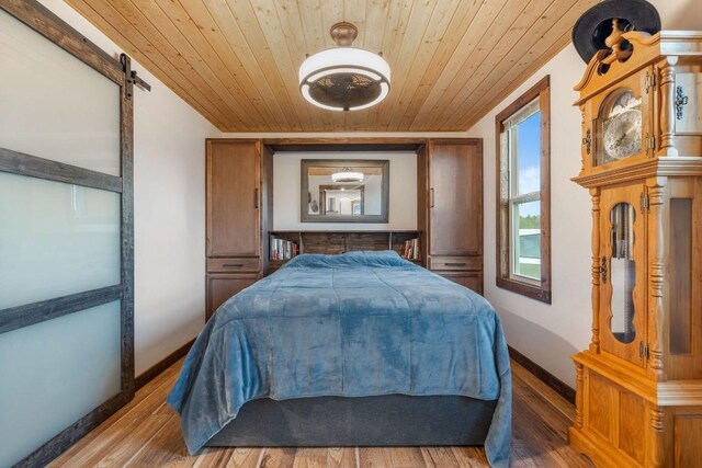 bedroom with hardwood / wood-style flooring, a barn door, and wooden ceiling