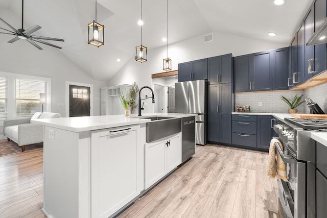 kitchen with a center island with sink, tasteful backsplash, pendant lighting, light wood-type flooring, and appliances with stainless steel finishes