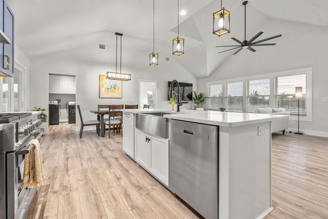 kitchen with light wood-type flooring, a center island with sink, pendant lighting, and appliances with stainless steel finishes