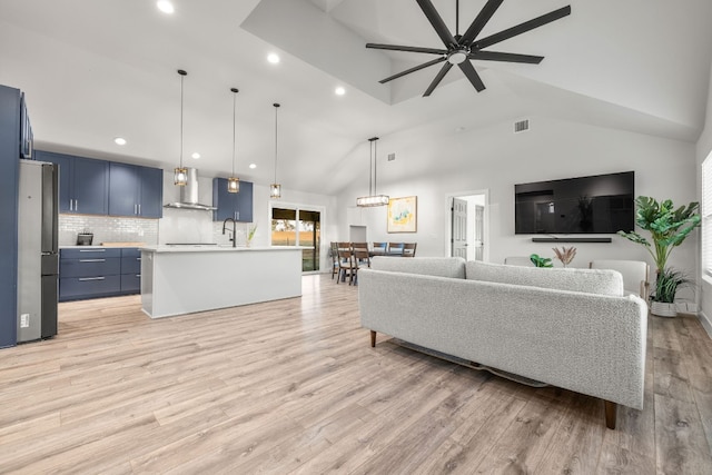 living room with light hardwood / wood-style floors, ceiling fan with notable chandelier, sink, and high vaulted ceiling