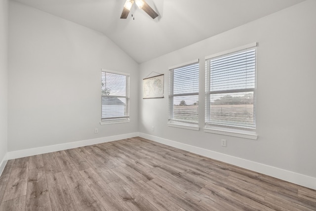 empty room with light hardwood / wood-style flooring, a healthy amount of sunlight, and vaulted ceiling