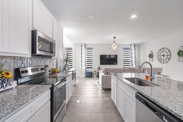 kitchen featuring white cabinets, sink, appliances with stainless steel finishes, and hanging light fixtures