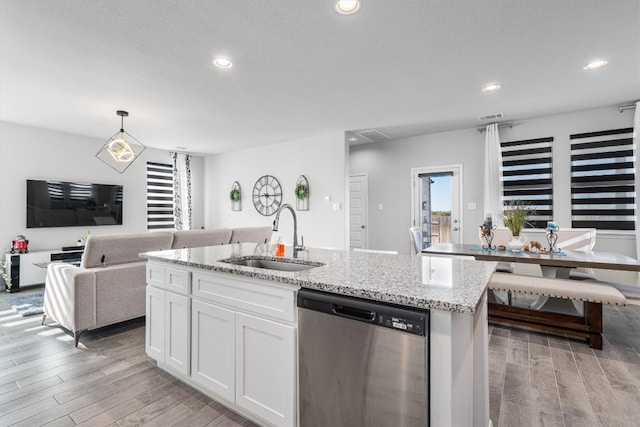 kitchen featuring white cabinets, sink, stainless steel dishwasher, light hardwood / wood-style floors, and decorative light fixtures