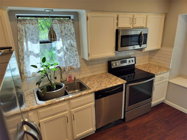 kitchen featuring white cabinets, backsplash, stainless steel appliances, and hanging light fixtures