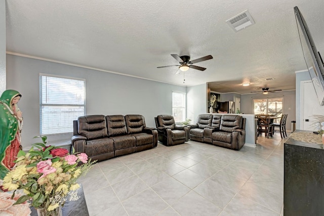 tiled living room with a textured ceiling, ceiling fan, and ornamental molding