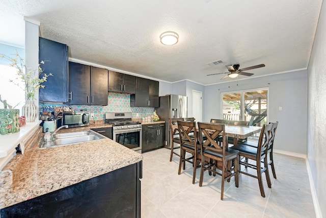 kitchen with stainless steel appliances, a textured ceiling, ceiling fan, decorative backsplash, and sink