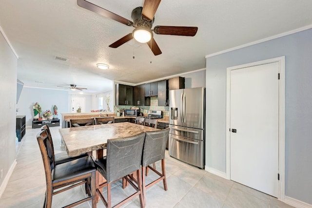 tiled dining space featuring ornamental molding, ceiling fan, and a textured ceiling