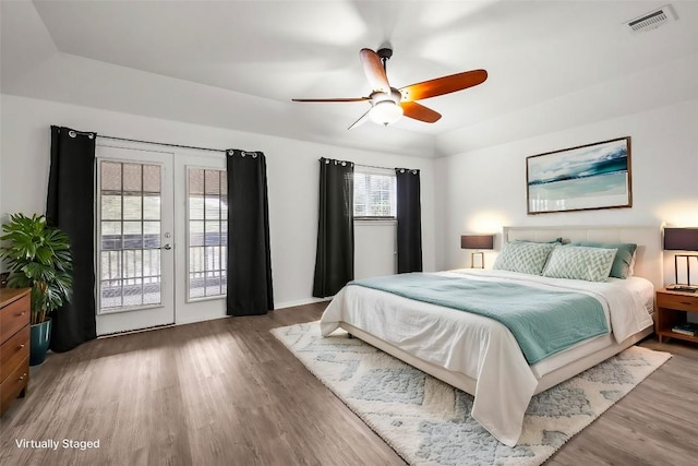 bedroom with a raised ceiling, ceiling fan, access to exterior, and wood-type flooring