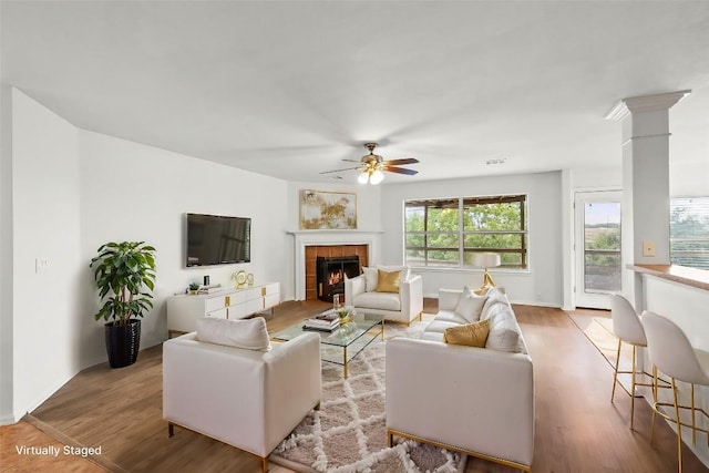 living room featuring a fireplace, light hardwood / wood-style flooring, and ceiling fan