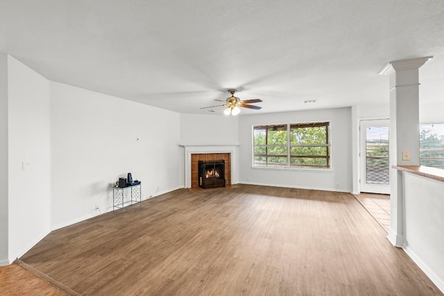 unfurnished living room featuring hardwood / wood-style flooring, ceiling fan, and a tiled fireplace