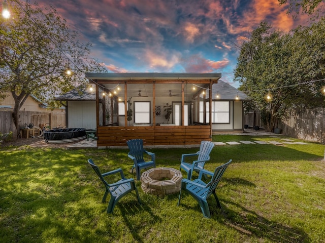 back house at dusk featuring a fire pit and a lawn