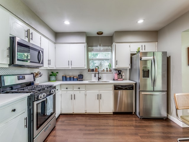 kitchen featuring stainless steel appliances, dark wood-type flooring, white cabinets, decorative backsplash, and sink