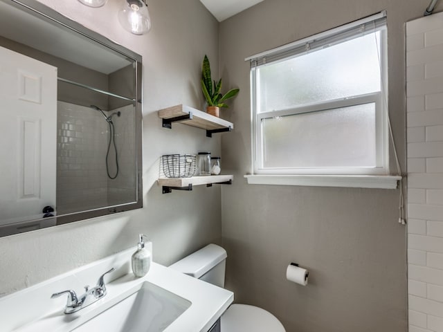 bathroom featuring tiled shower, toilet, and vanity