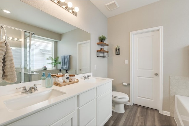 bathroom featuring a washtub, hardwood / wood-style floors, vanity, and toilet