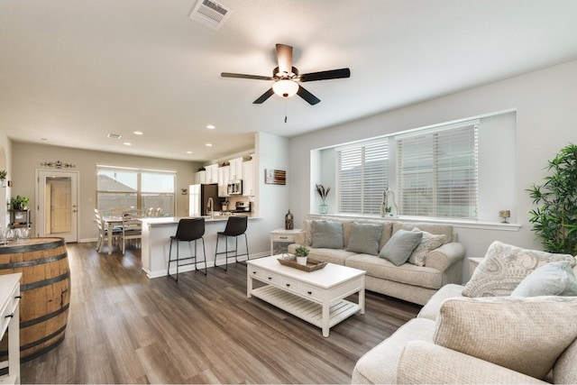 living room featuring ceiling fan and dark hardwood / wood-style floors