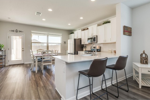 kitchen featuring a kitchen breakfast bar, kitchen peninsula, white cabinetry, and stainless steel appliances