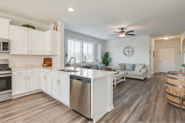 kitchen featuring white cabinetry, ceiling fan, stainless steel appliances, kitchen peninsula, and hardwood / wood-style flooring