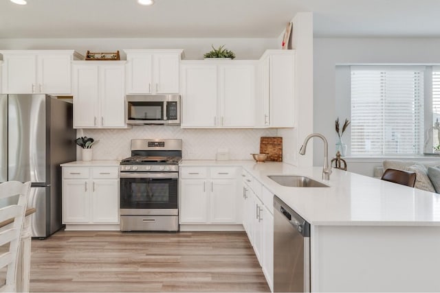 kitchen with white cabinets, stainless steel appliances, light hardwood / wood-style flooring, and sink