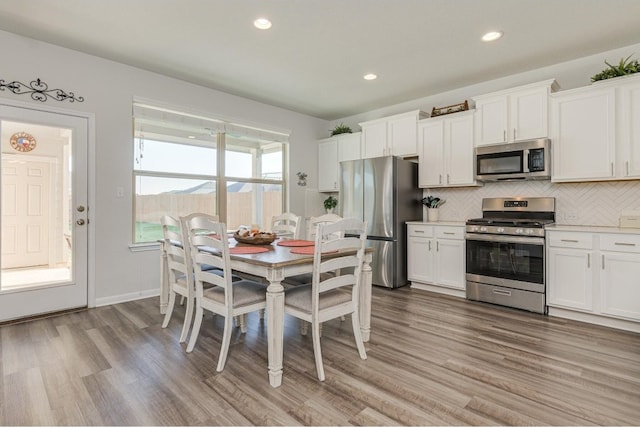 kitchen with decorative backsplash, light hardwood / wood-style floors, white cabinetry, and stainless steel appliances