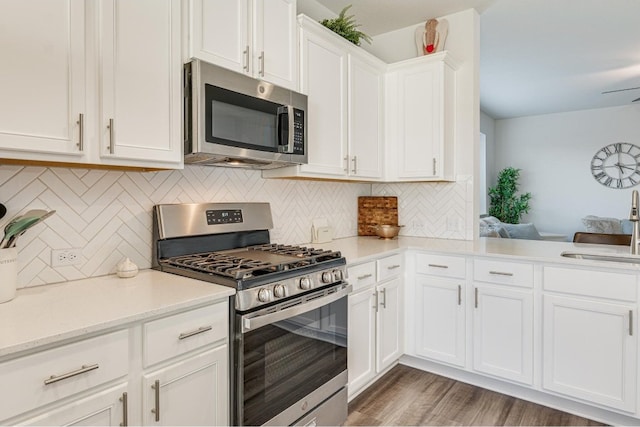 kitchen featuring white cabinetry, sink, dark hardwood / wood-style floors, decorative backsplash, and appliances with stainless steel finishes