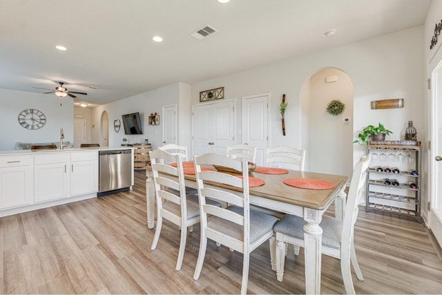 dining space with ceiling fan, sink, and light wood-type flooring