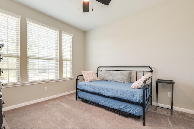 bedroom featuring ceiling fan, light carpet, and multiple windows