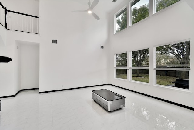 unfurnished living room with a towering ceiling, a wealth of natural light, and ceiling fan