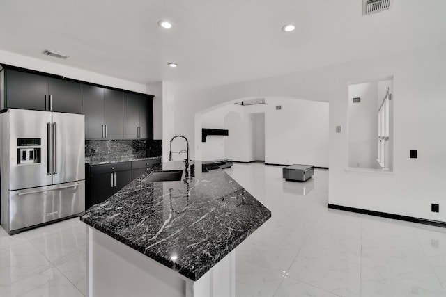 kitchen featuring tasteful backsplash, dark stone counters, sink, kitchen peninsula, and high end fridge