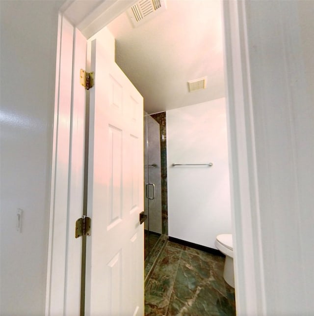 bathroom with toilet and a shower with shower door