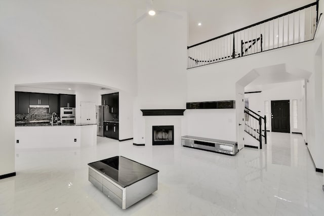 living room featuring a towering ceiling, a tiled fireplace, and sink