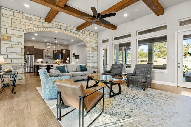 living room featuring ceiling fan, light hardwood / wood-style floors, and beamed ceiling