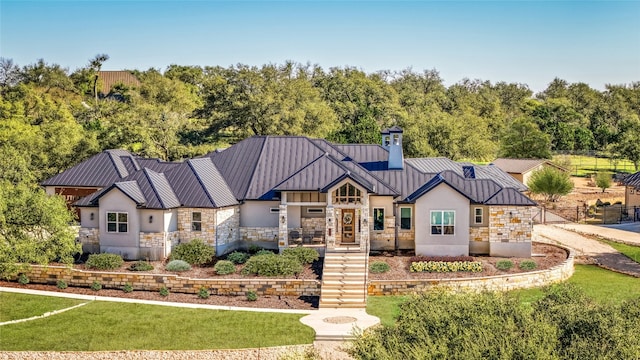 modern inspired farmhouse featuring metal roof, stone siding, a standing seam roof, and stucco siding