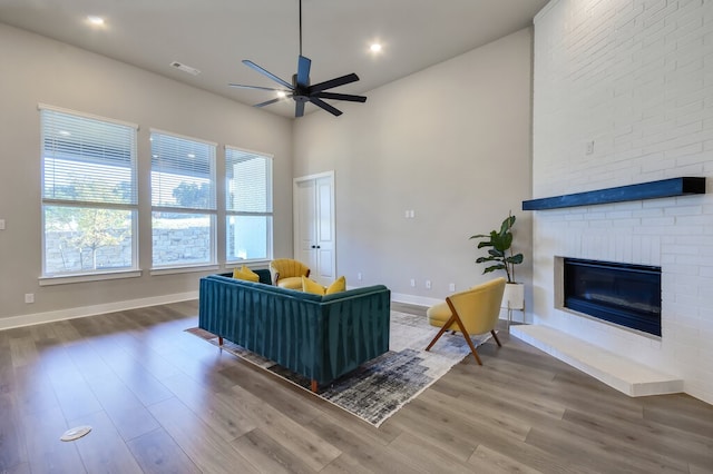 living room featuring wood-type flooring, ceiling fan, and a fireplace