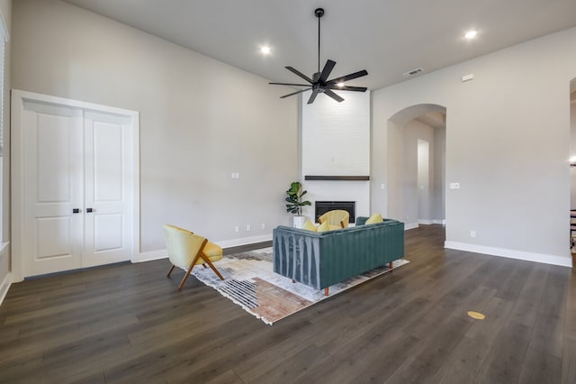 unfurnished living room featuring ceiling fan, dark hardwood / wood-style floors, and a large fireplace